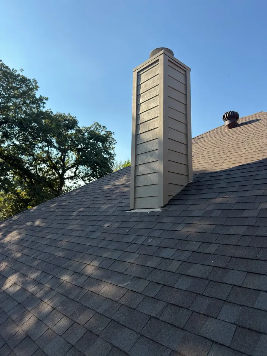 Completed chimney with new siding and paint above shingle roof