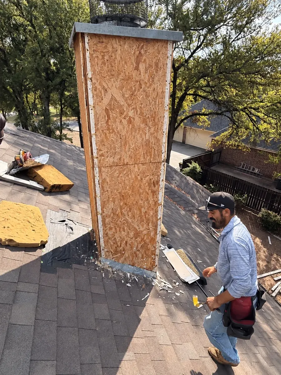 Worker beside exposed chimney during siding replacement project