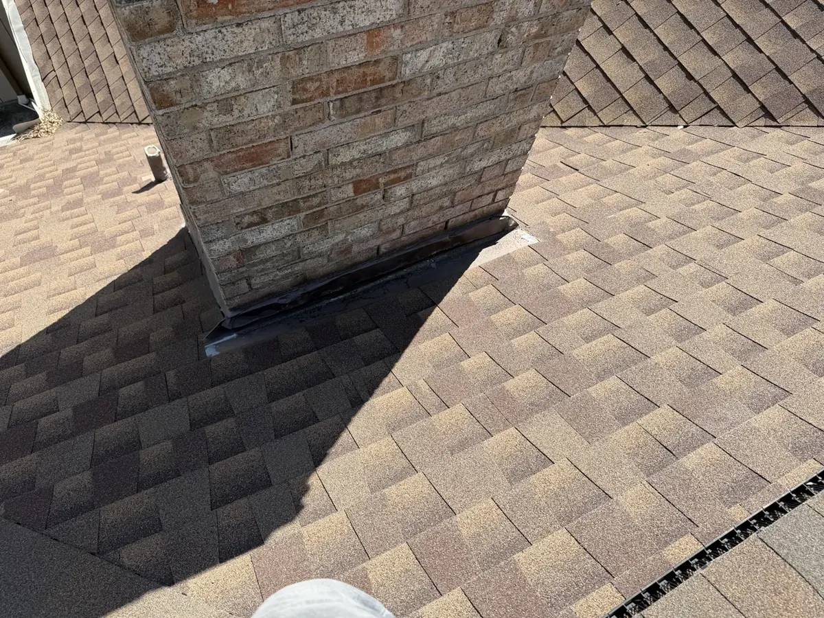 Overview of brick chimney roof flashing and surrounding shingles